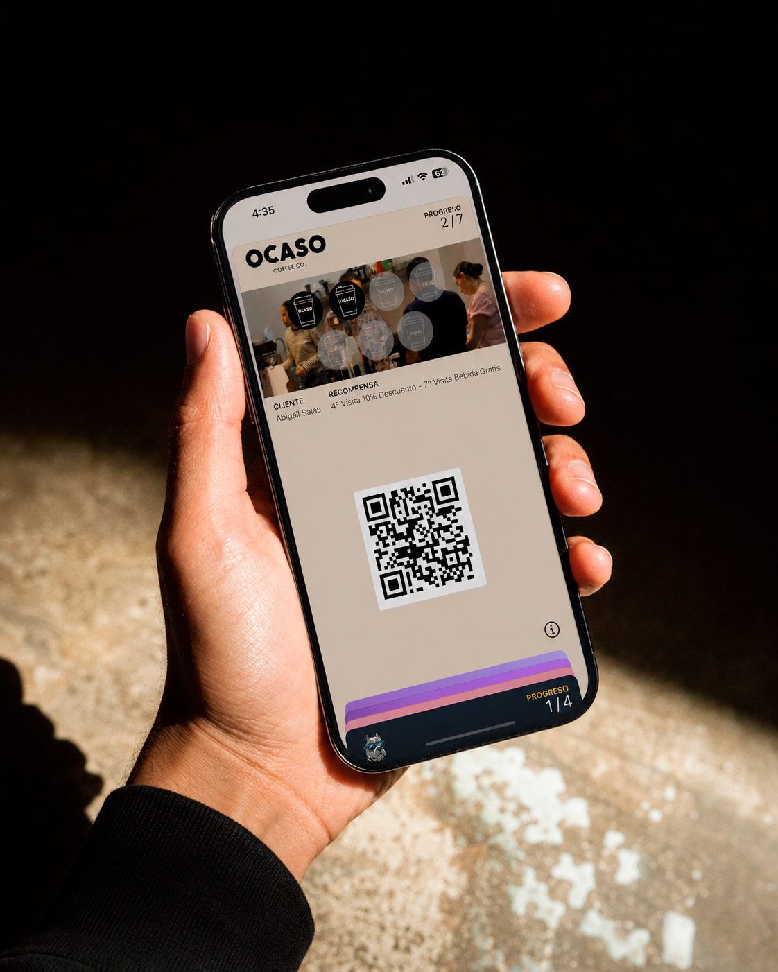 Cliente sosteniendo su tarjeta de lealtad de Ocaso Coffee Co. en Apple Wallet, con el QR listo para escanear